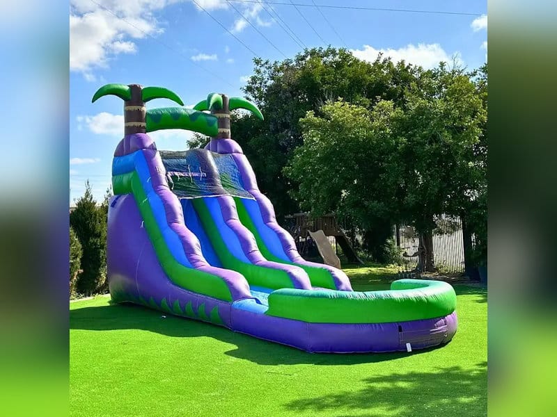 Purple and green tropical inflatable waterslide with palm tree decorations
