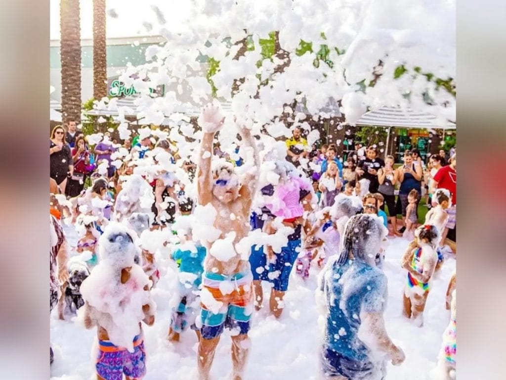 Children playing outdoors in a foam party covered in white foam