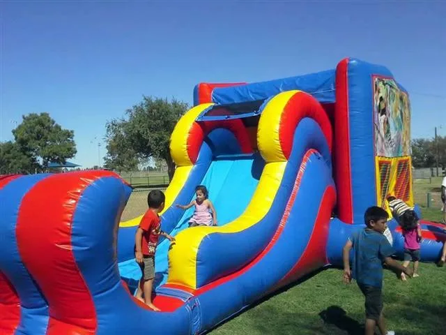 Large red and blue inflatable bounce house and slide combo with children playing