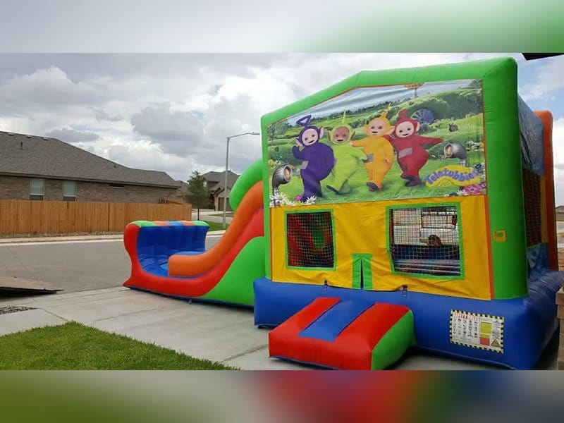 Green and red inflatable combo bounce house with an attached slide, set up on a driveway